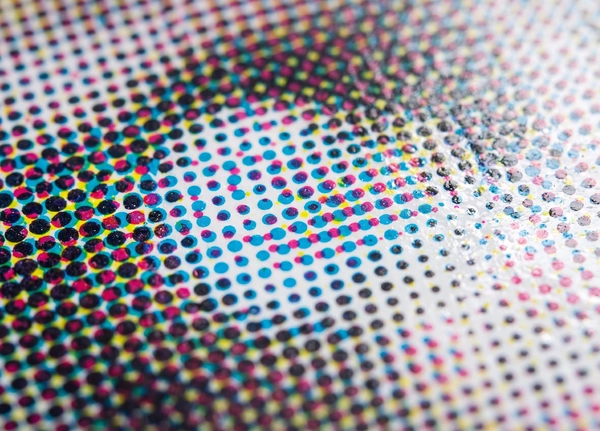 macro detail of the intricate, dotted halftone pattern of a commercial print job on a piece of glossy paper